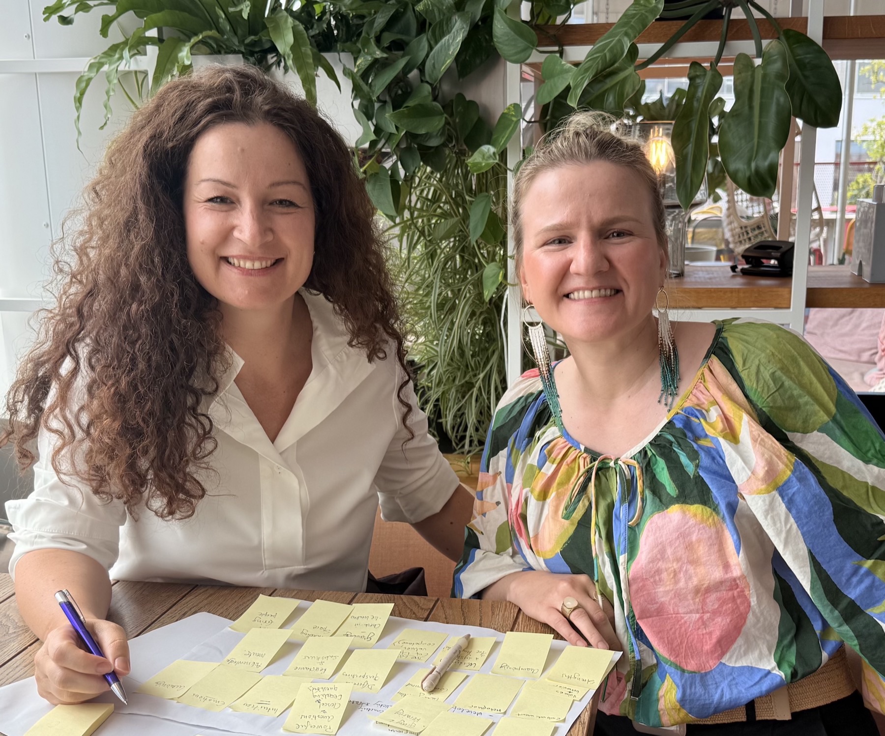 Migena Gjerazi and Anna Korosadowicz smiling at a table covered in sticky notes