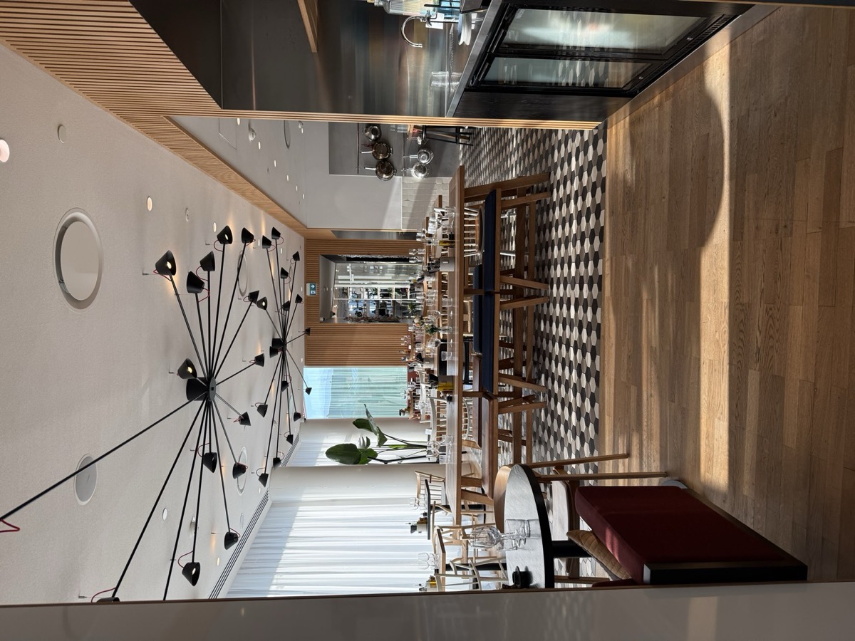 The Living Kitchen at Zoku Copenhagen: long wooden tables under a large black chandelier