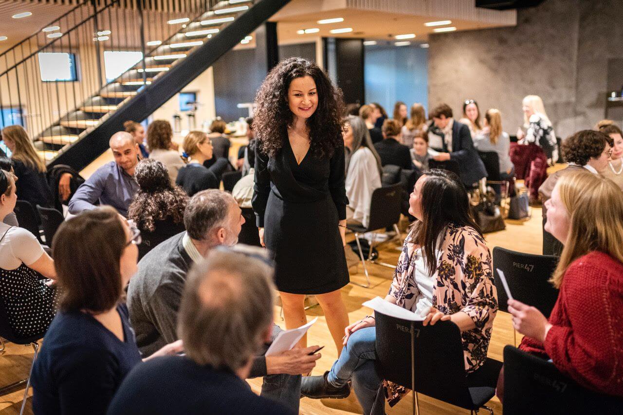 Migena facilitating a workshop in a full room