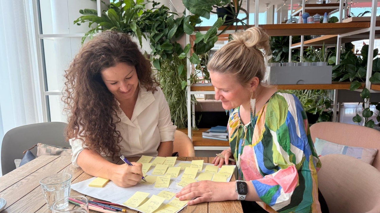 Migena and Anna planning with sticky notes at a table